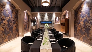 A conference room with a long table, black chairs, and a floral centerpiece.