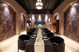Un salón de conferencias con una larga mesa, sillas negras y un centro de mesa floral.