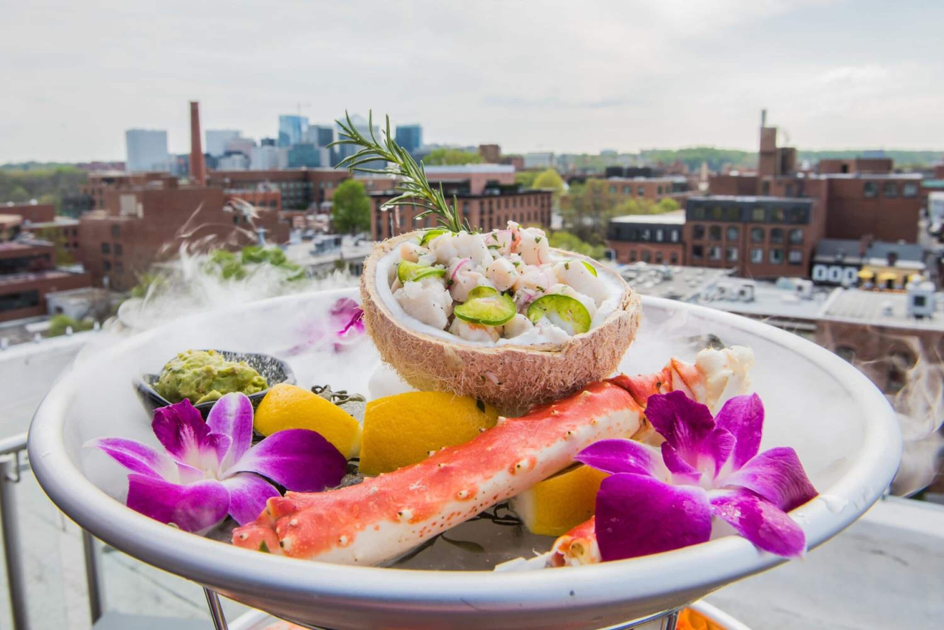 A seafood platter with shrimp, crab, and avocado on a rooftop with a cityscape view.