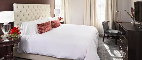 A hotel room with a large bed, a desk, a chair, and a television.