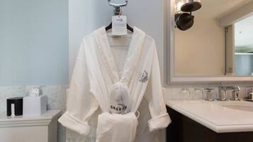 Une salle de bain avec un peignoir blanc suspendu à un porte-serviettes, un miroir et un lavabo.