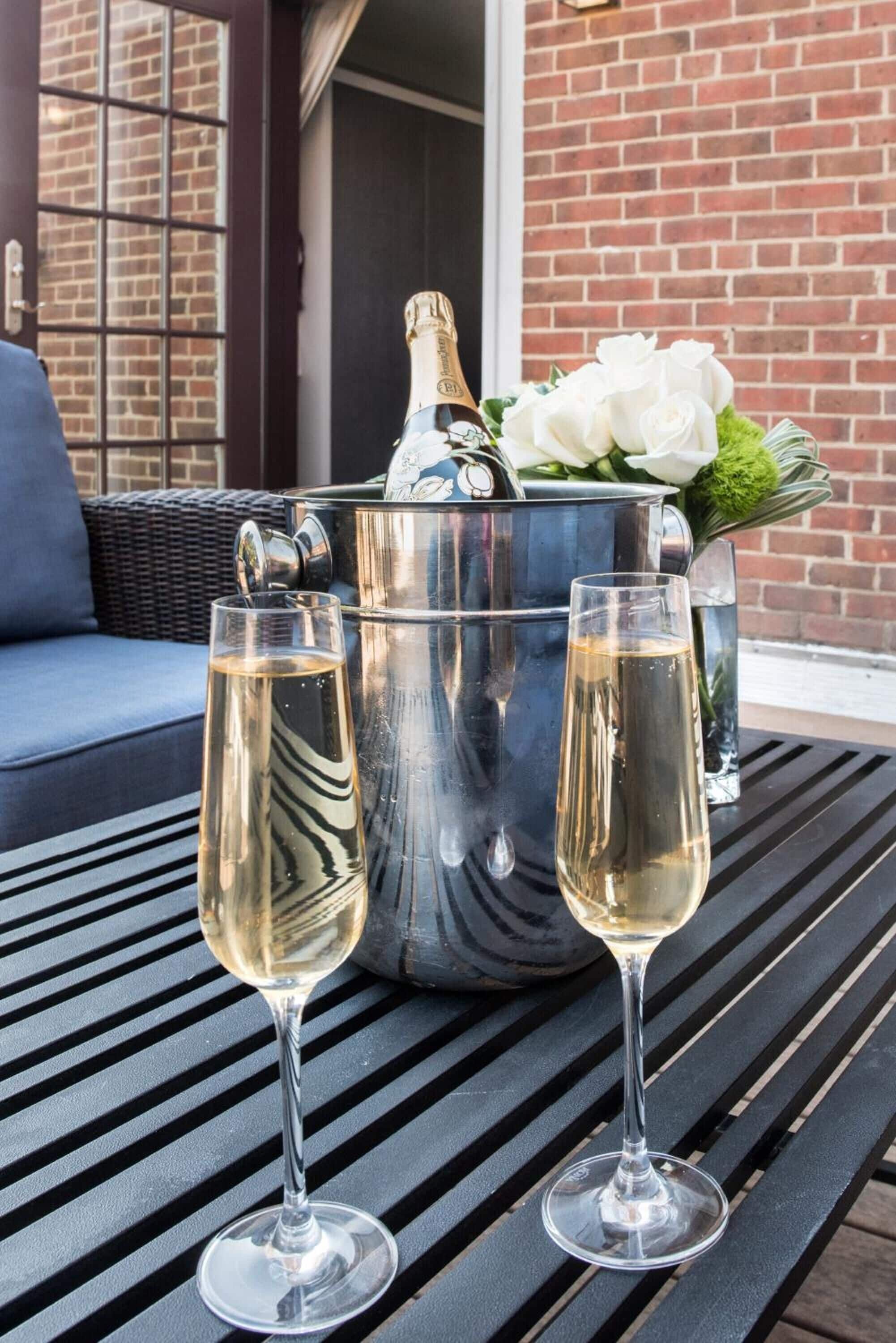 A table with two champagne glasses and a champagne bucket with flowers.