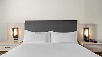 A hotel room with a large bed, two bedside tables, and two wall-mounted lamps.