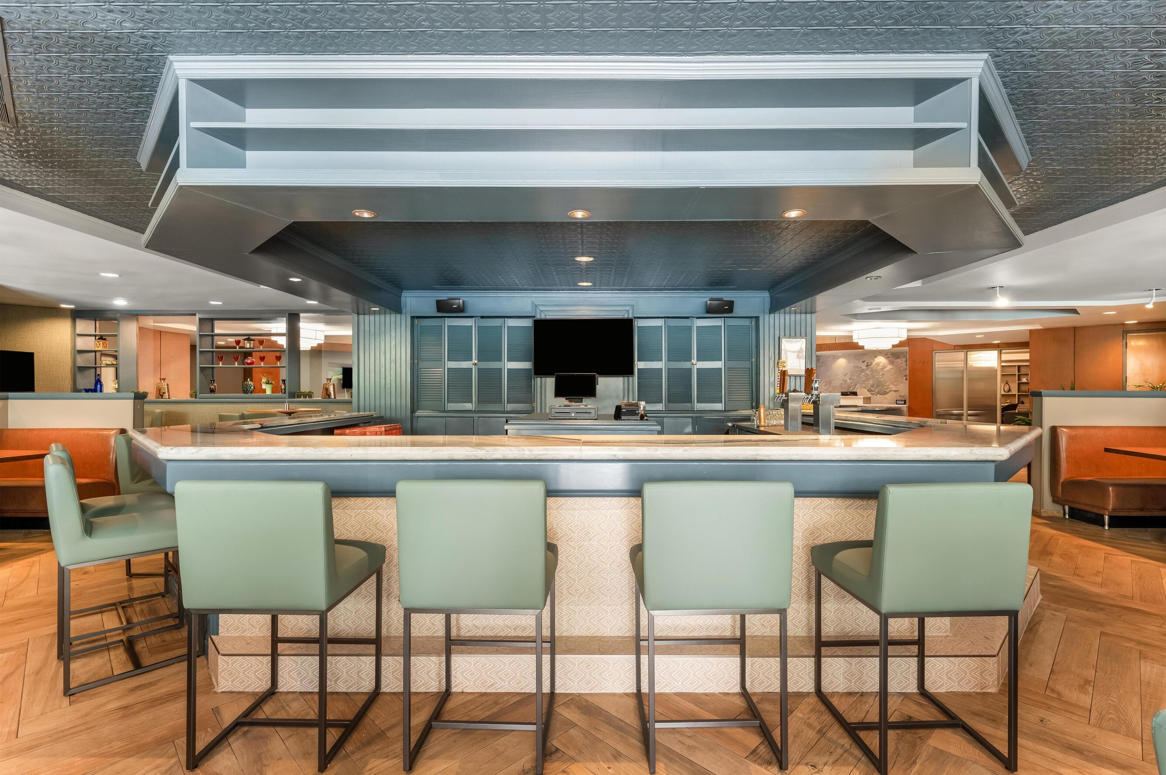 Uma cozinha moderna com ilha central, banquetas de bar e uma televisão de tela plana grande.