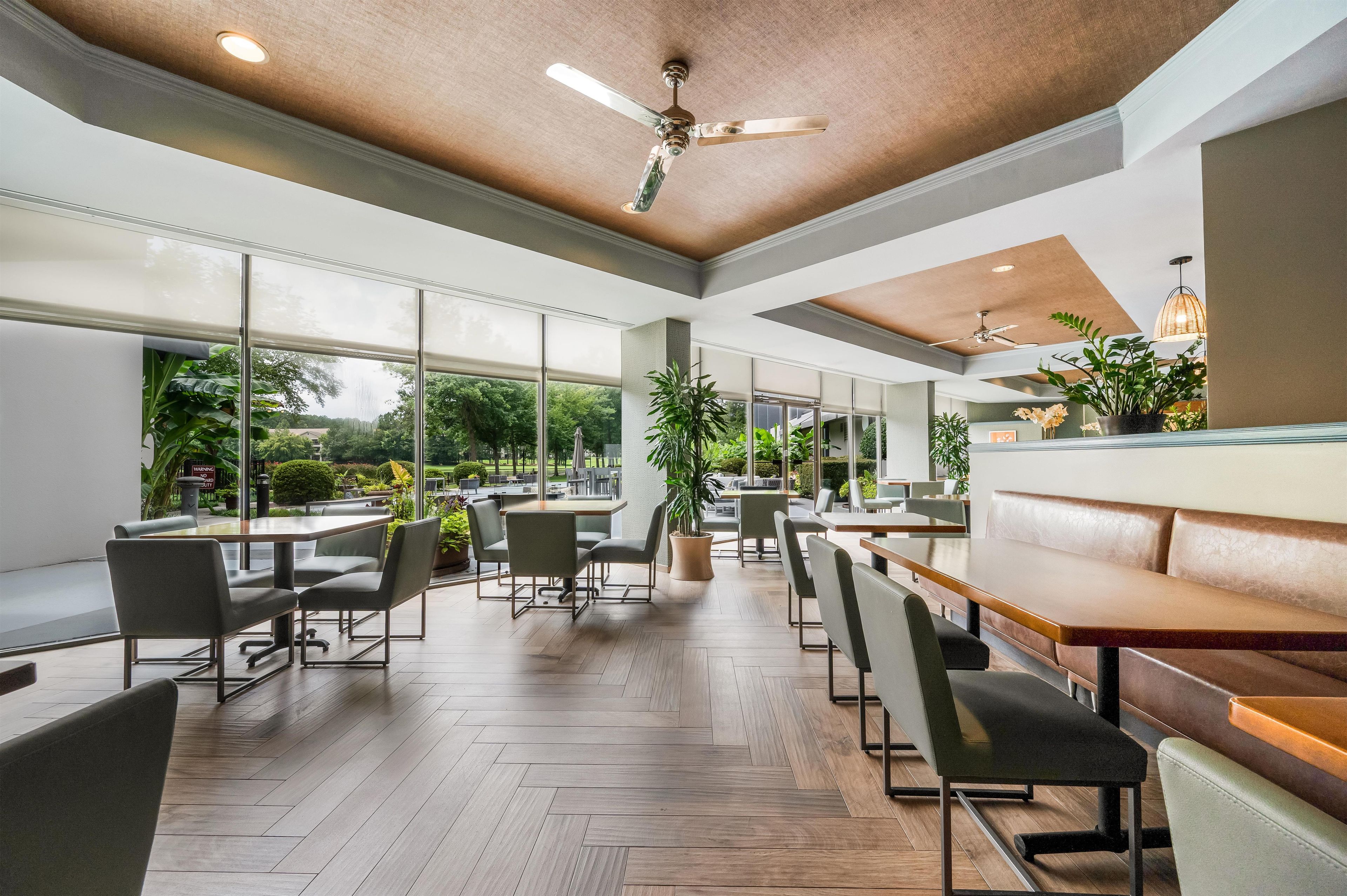 A spacious indoor dining area with high ceilings, large windows, and modern furniture.