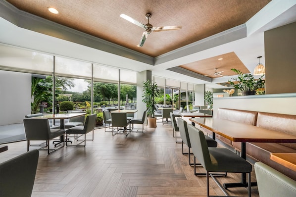 A spacious indoor dining area with high ceilings, large windows, and modern furniture. - DoubleTree Suites by Hilton Raleigh - Durham (Durham)
