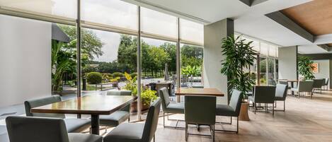 Un espacio interior amplio con ventanas grandes, piso de madera y mobiliario moderno.