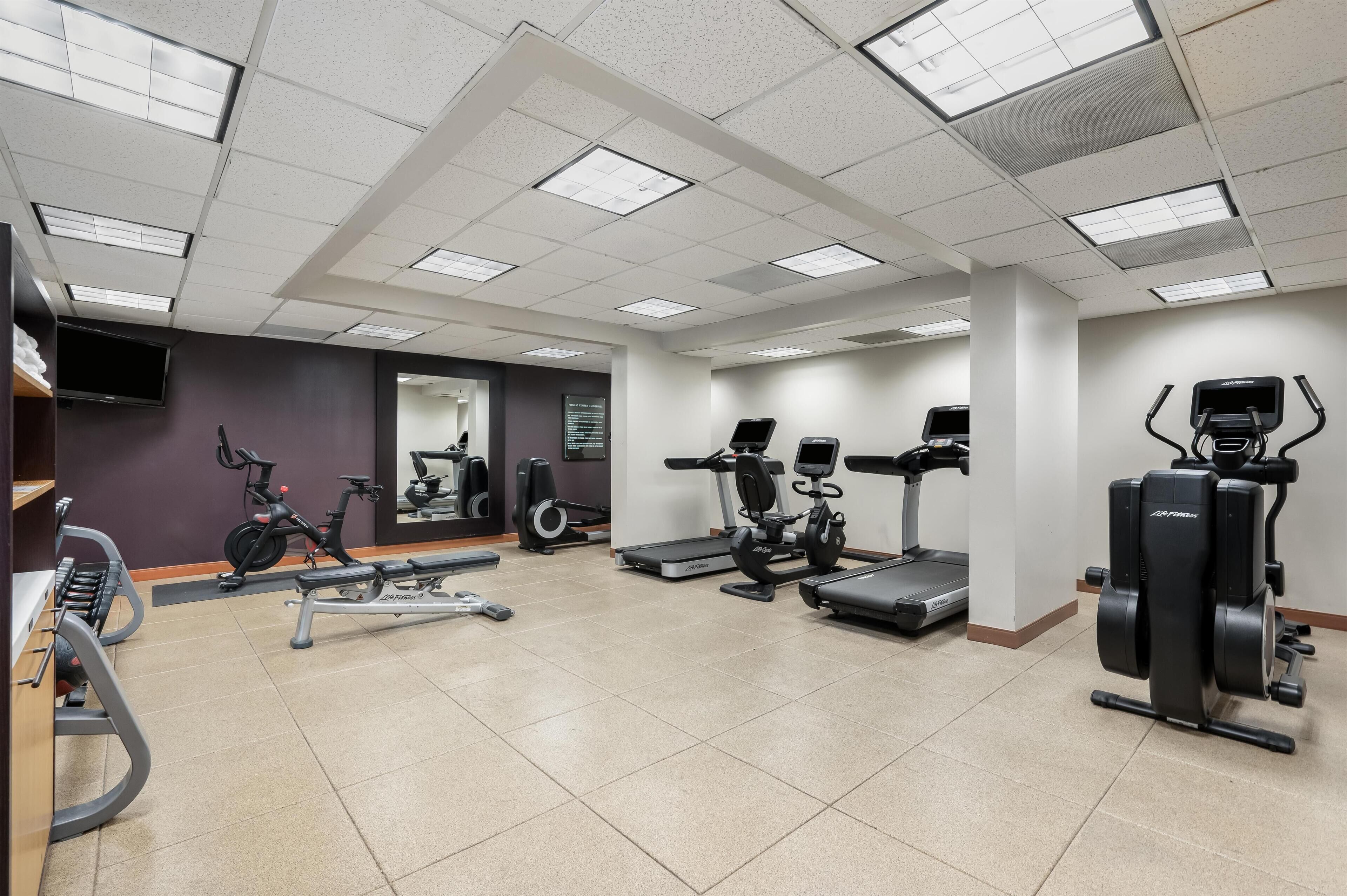 A gym with various exercise equipment, including treadmills, stationary bikes, and weight machines.