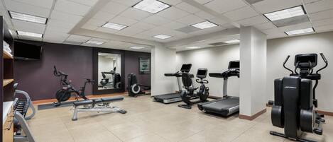 A gym with various exercise equipment, including treadmills, stationary bikes, and weight machines.