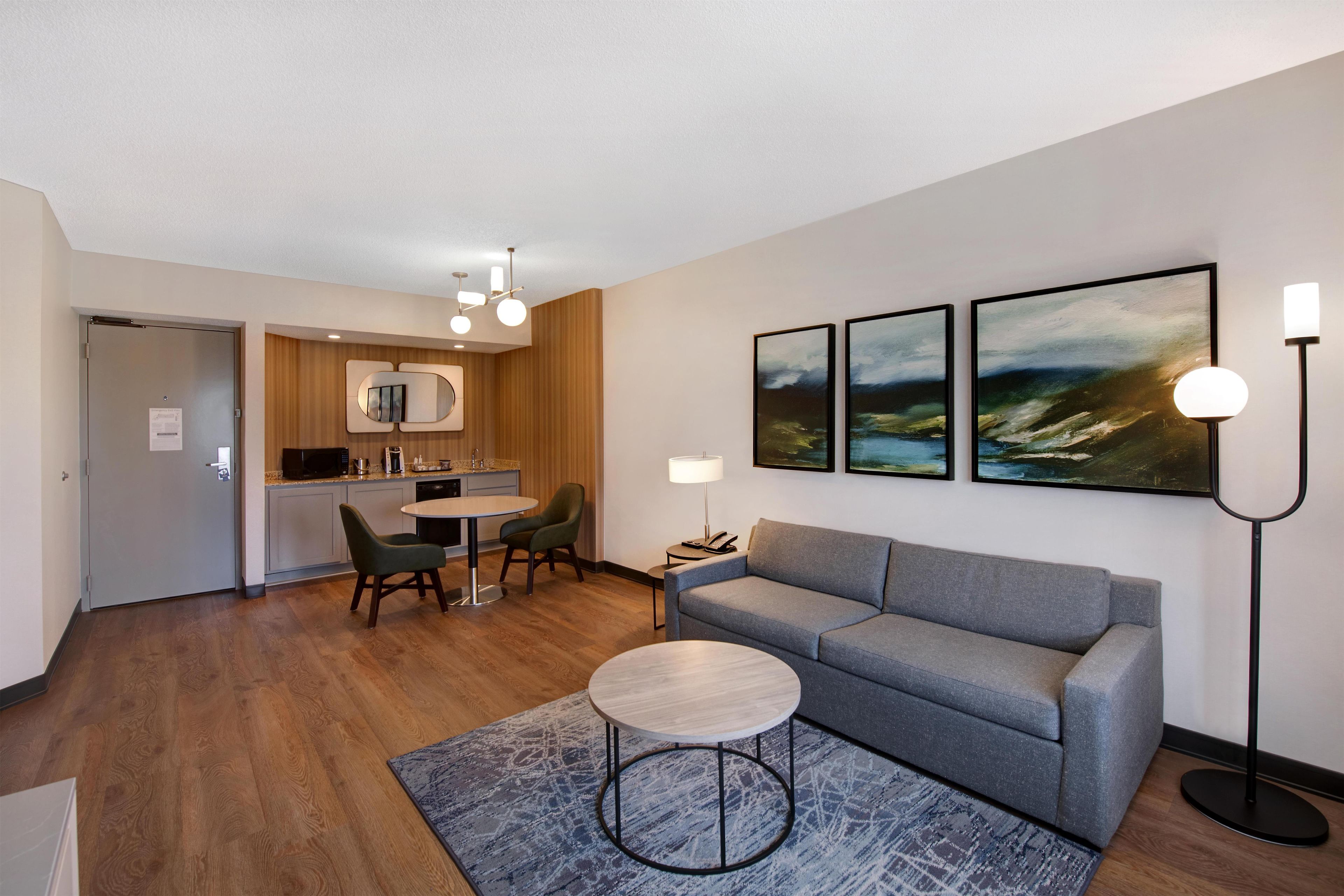 A modern living room with a grey sofa, a round coffee table, and a blue patterned rug.