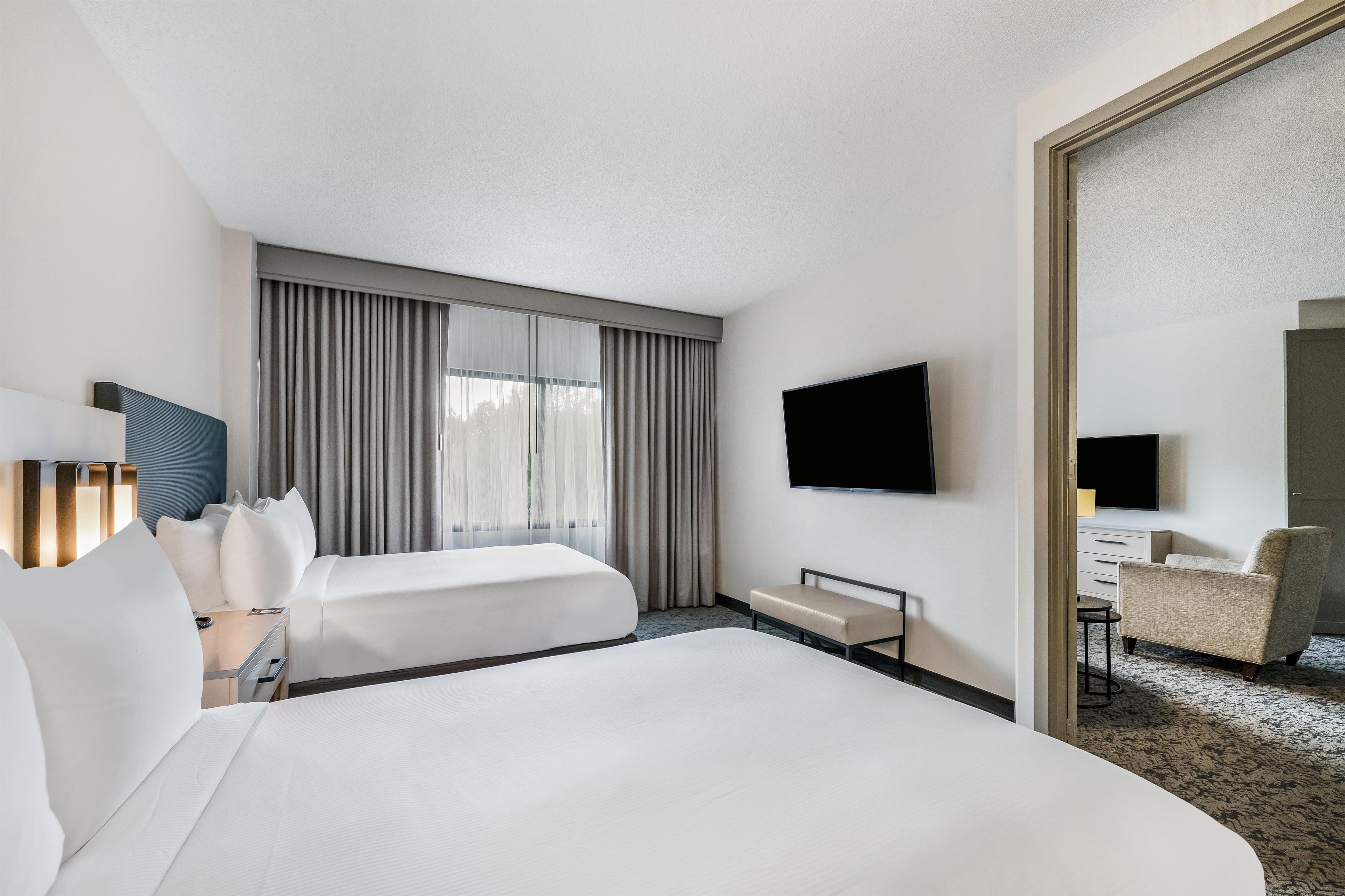 A hotel room with two beds, a flat-screen TV, a desk, and a chair.