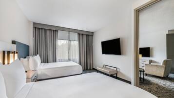 A hotel room with two beds, a flat-screen TV, a desk, and a chair.