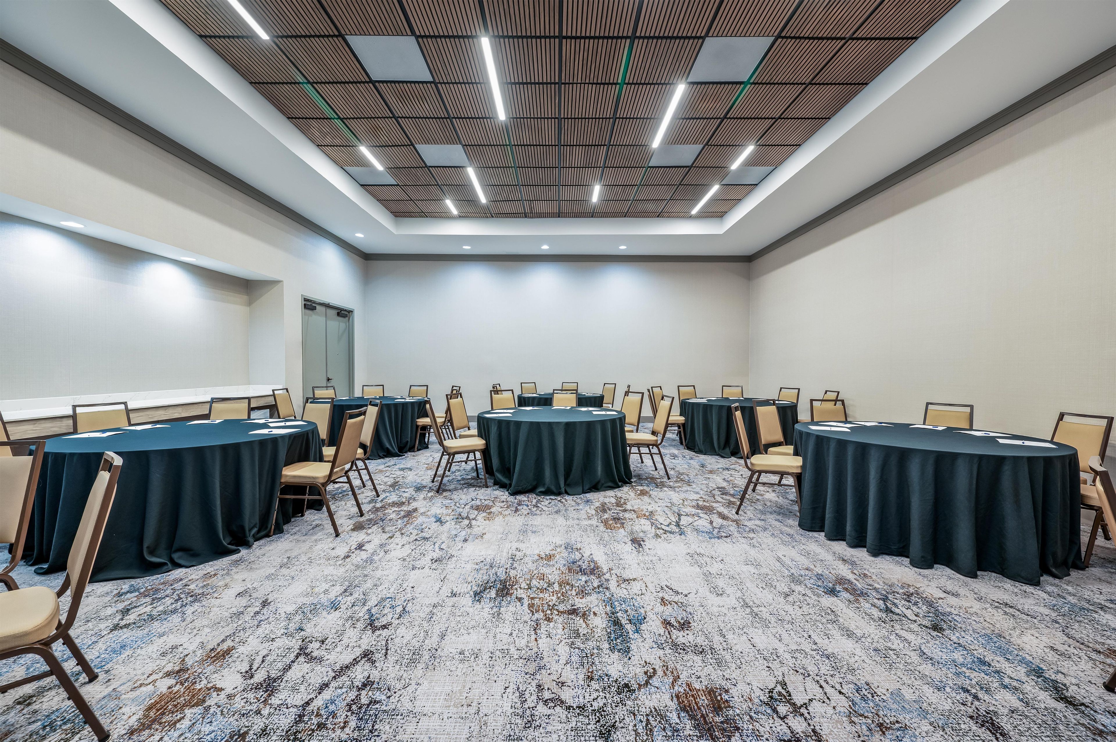 A conference room with round tables, chairs, and a patterned carpet.