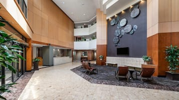 A spacious lobby with a high ceiling, a reception desk, seating area, and a wall-mounted decorative element.