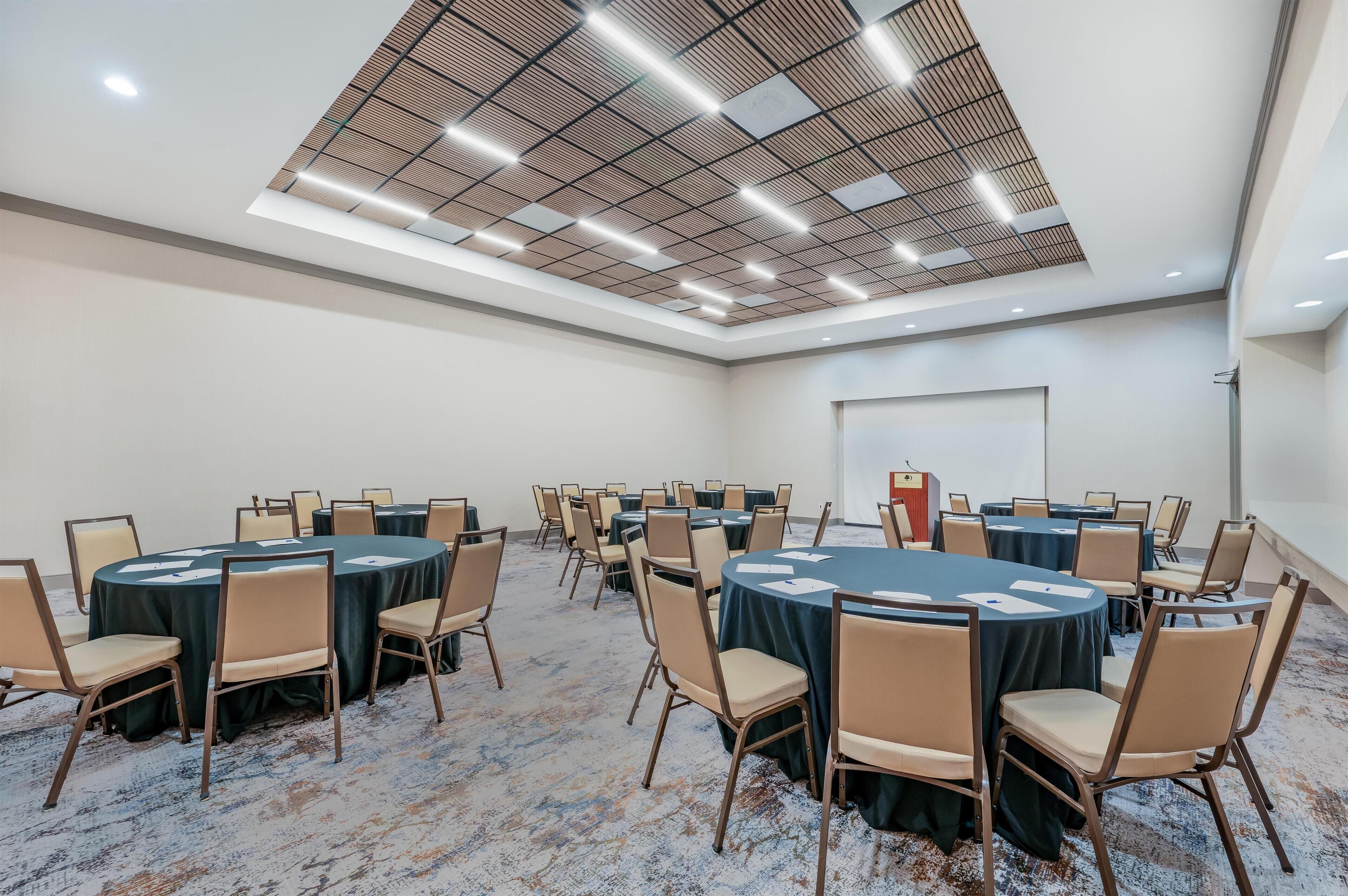 A conference room with round tables, chairs, and a podium.