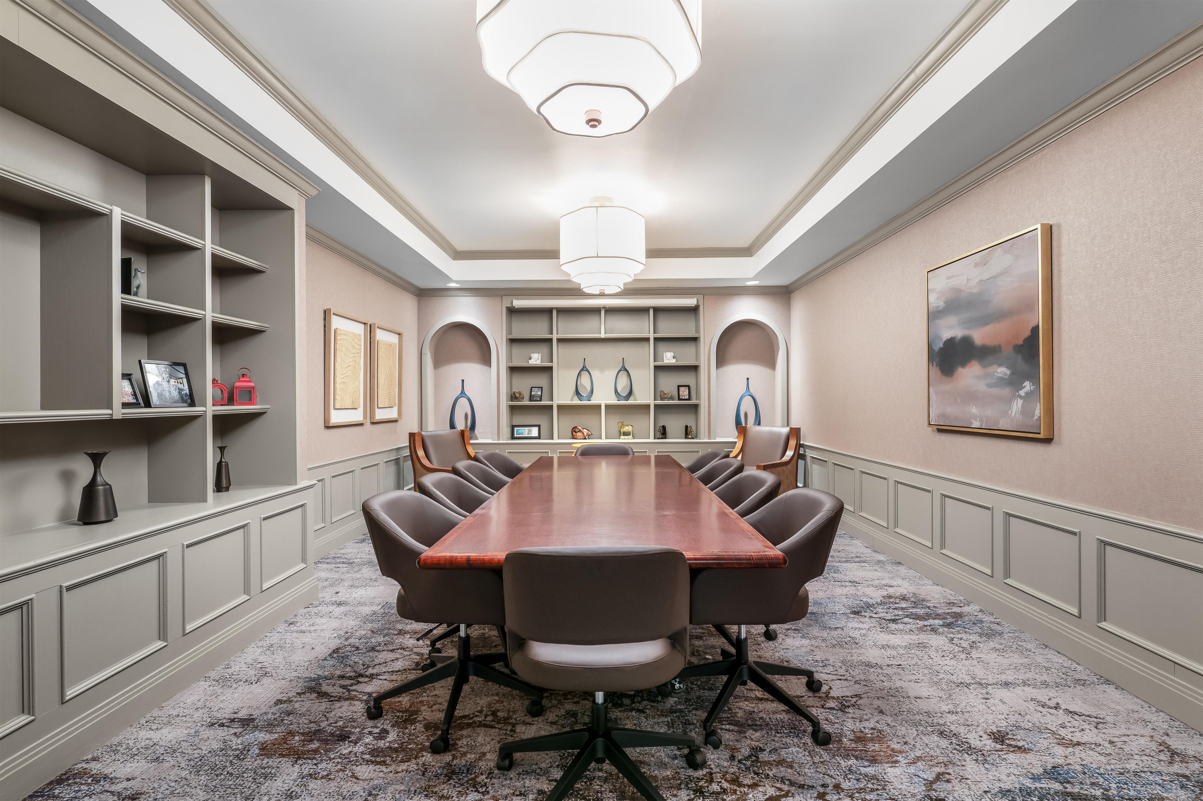 Un salón de conferencias con una larga mesa, sillas y estanterías decoradas.