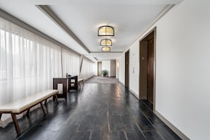 A hotel hallway with a bench, a reception desk, and a plant. - DoubleTree Suites by Hilton Raleigh - Durham (Durham)