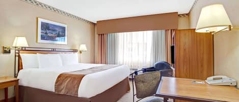 Une chambre d’hôtel avec un grand lit, un bureau avec un téléphone et une chaise.