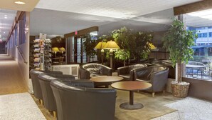 A lobby with leather sofas, round tables, and a reception desk. - Travelodge by Wyndham Seattle By The Space Needle (Seattle)