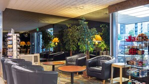 A cozy lounge area with leather chairs, a coffee table, and a shelf with mugs. - Travelodge by Wyndham Seattle By The Space Needle (Seattle)
