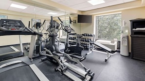 Une salle de sport équipée de tapis de course, de vélos elliptiques et d’haltères.