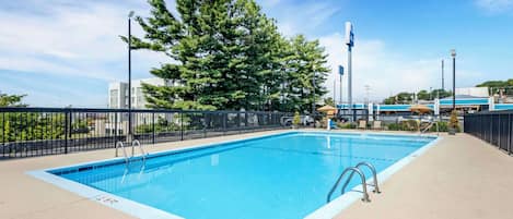 A rectangular swimming pool with a blue edge, surrounded by a black metal fence.