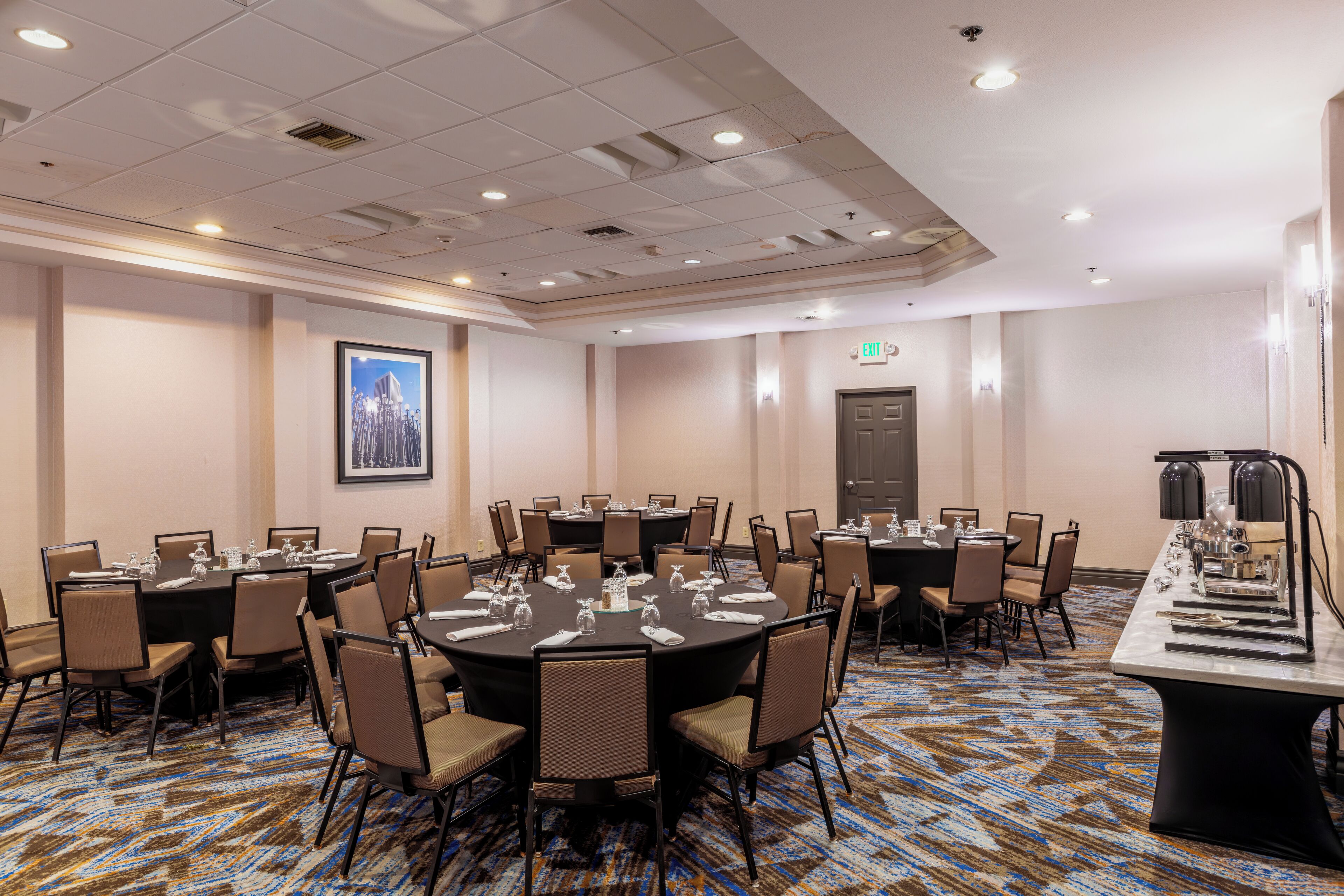 A conference room with multiple tables, chairs, and a carpeted floor.