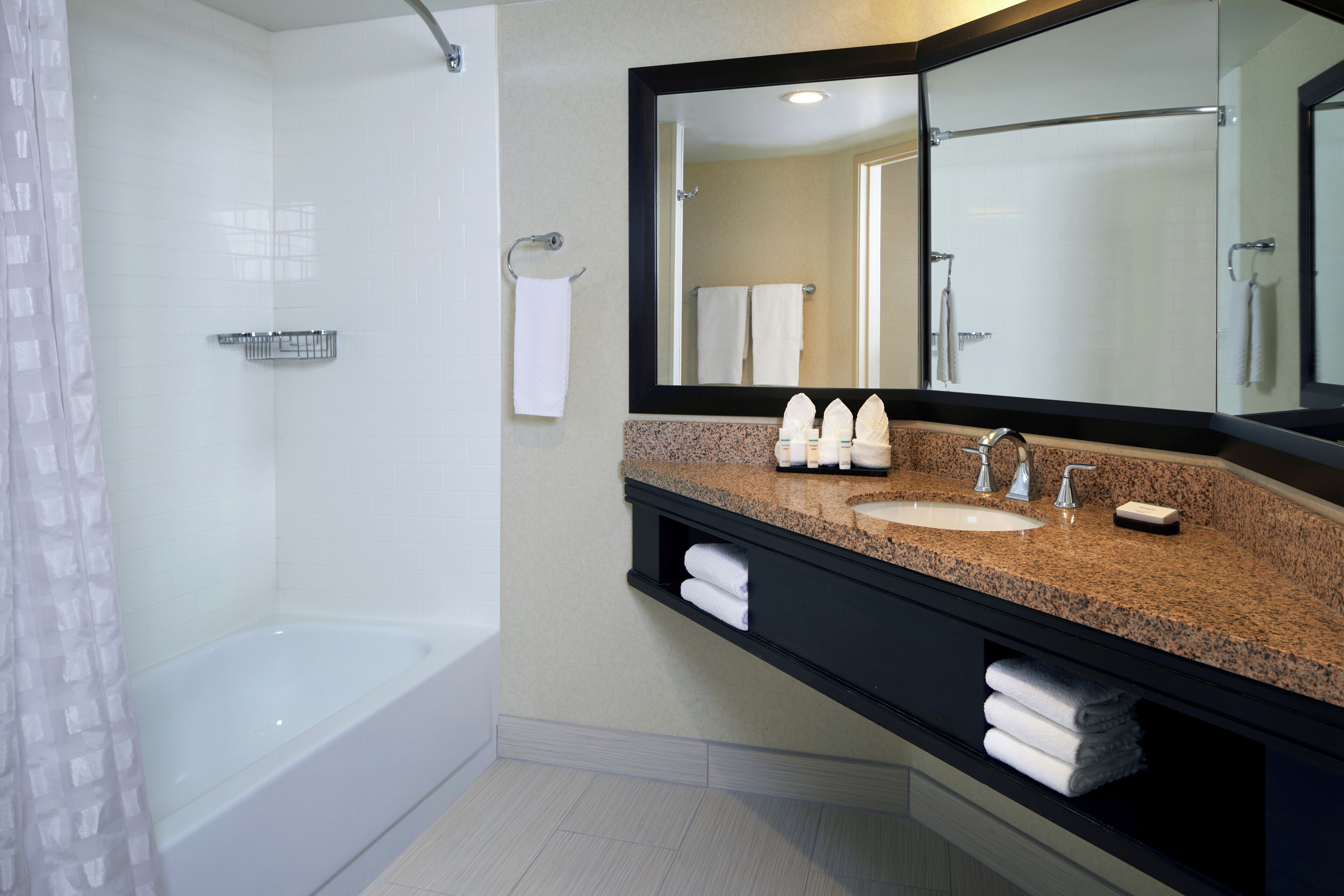 A bathroom with a bathtub, a sink, a mirror, and a towel rack.