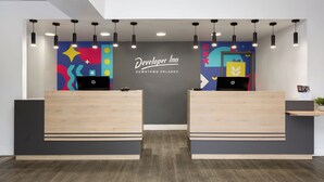 Una reception con due laptop HP, un murale colorato e un cartello che recita 'Developer Inn Downtown Orlando'.