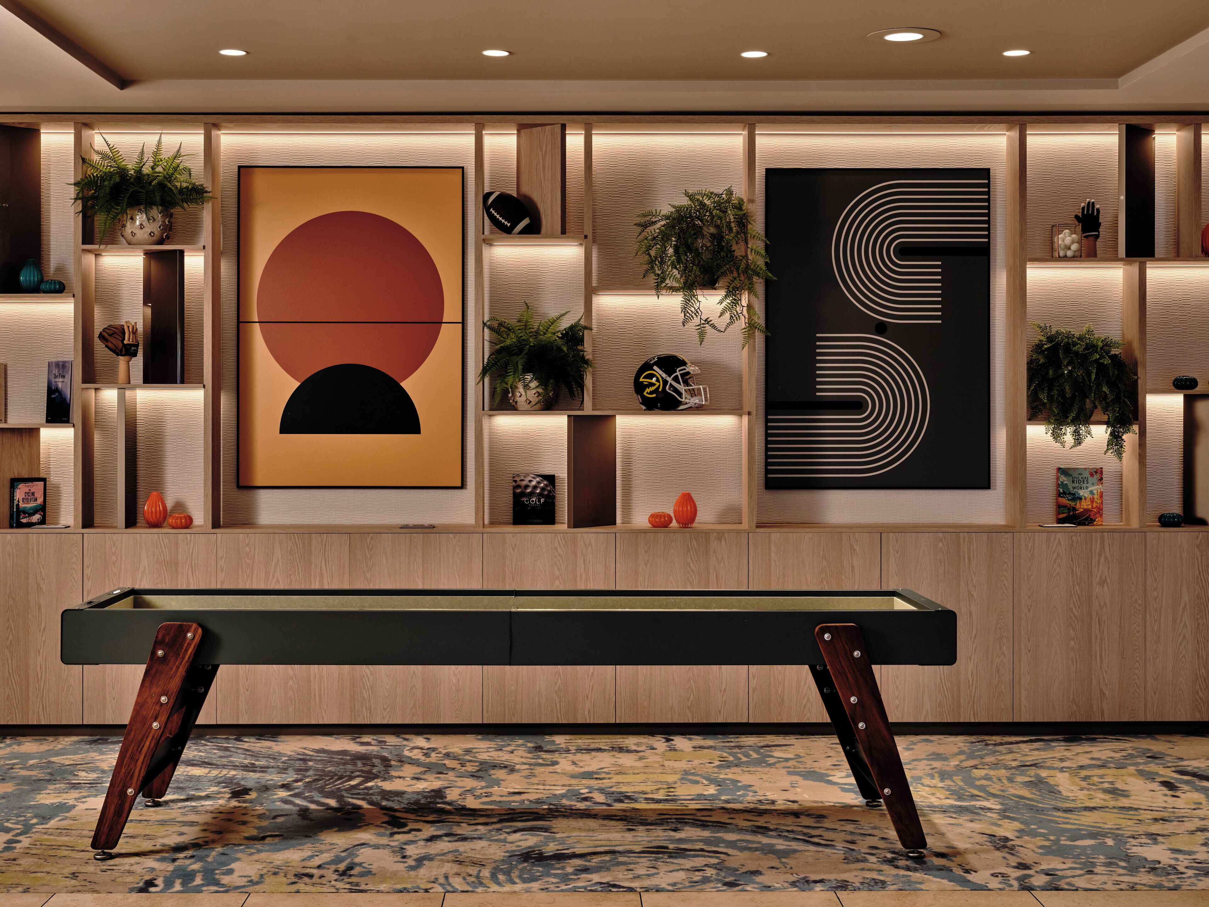 A modern interior with a pool table, wooden paneling, and artwork.