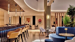 A modern bar area with high stools, a round table, and a blue sofa. - Crowne Plaza Bratislava by IHG (Bratislava)