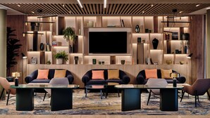 A modern living room with a large flat-screen TV, multiple seating areas, and built-in shelving with decorative items. - Crowne Plaza Bratislava by IHG (Bratislava)