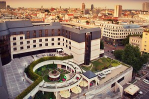 A modern hotel with a central courtyard, multiple floors, and a mix of residential and commercial buildings in the background. - Crowne Plaza Bratislava by IHG (Bratislava)