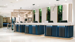 A modern reception area with a marble counter, blue and beige decor, and vertical greenery accents. - Crowne Plaza Bratislava by IHG (Bratislava)