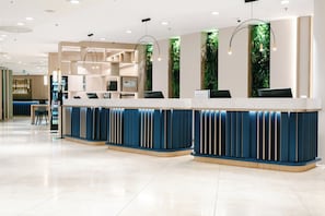 A modern reception area with a marble counter, blue and beige decor, and vertical greenery accents. - Crowne Plaza Bratislava by IHG (Bratislava)