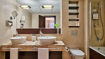 Een moderne badkamer met twee wastafels, een toilet, een douche en een grote spiegel.