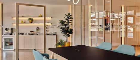 A modern meeting room with a black table, teal chairs, and a glass partition.