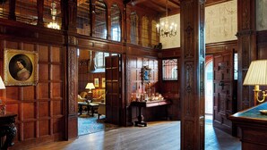 A grand room with wooden paneling, a chandelier, and a large window with a view. - Hanbury Manor Marriott Hotel & Country Club (Ware)