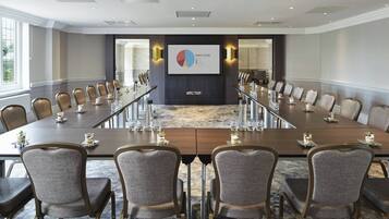 A conference room with a long table, multiple chairs, and a presentation screen displaying a market share pie chart.