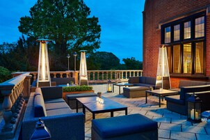 Un patio al aire libre con arreglos de asientos, mesas e iluminación decorativa.