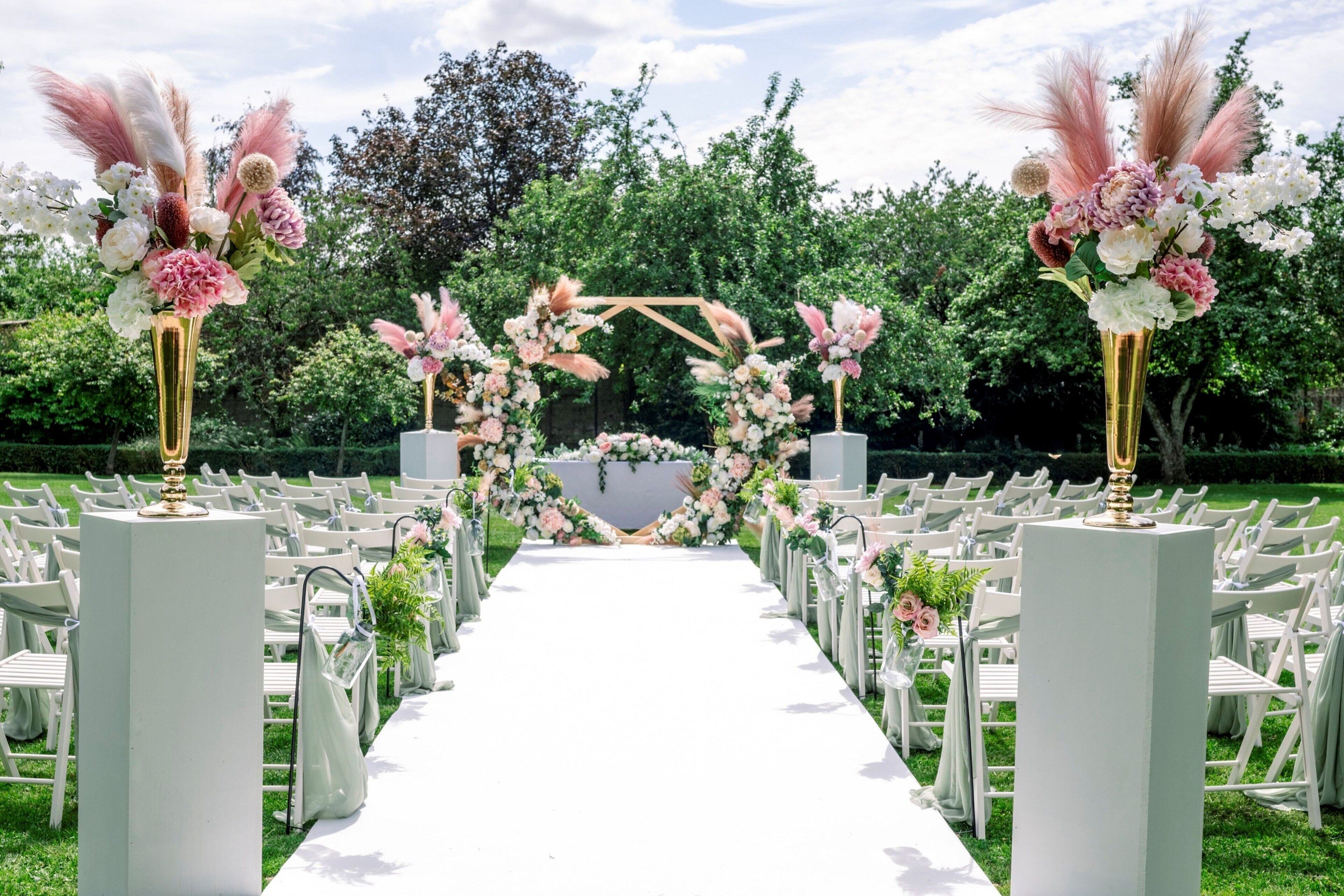 A wedding aisle with white chairs and a floral archway.