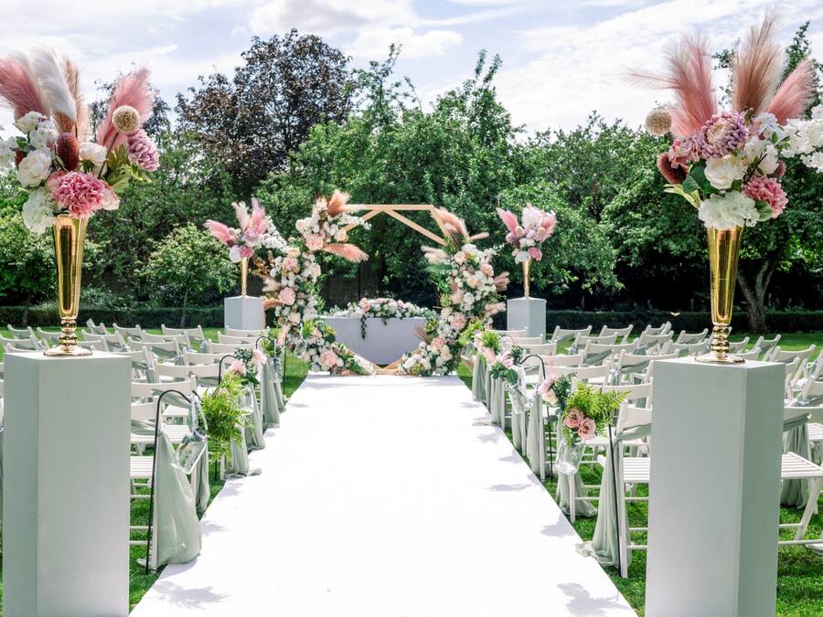 A wedding aisle with white chairs and a floral archway.