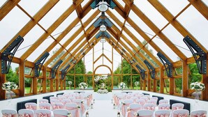 A large, open hall with a high ceiling and wooden beams, arranged in rows for seating. - Hanbury Manor Marriott Hotel & Country Club (Ware)