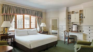 Habitación de hotel con una cama grande, dos mesitas de noche con lámparas, un escritorio con silla, un armario y un espejo.