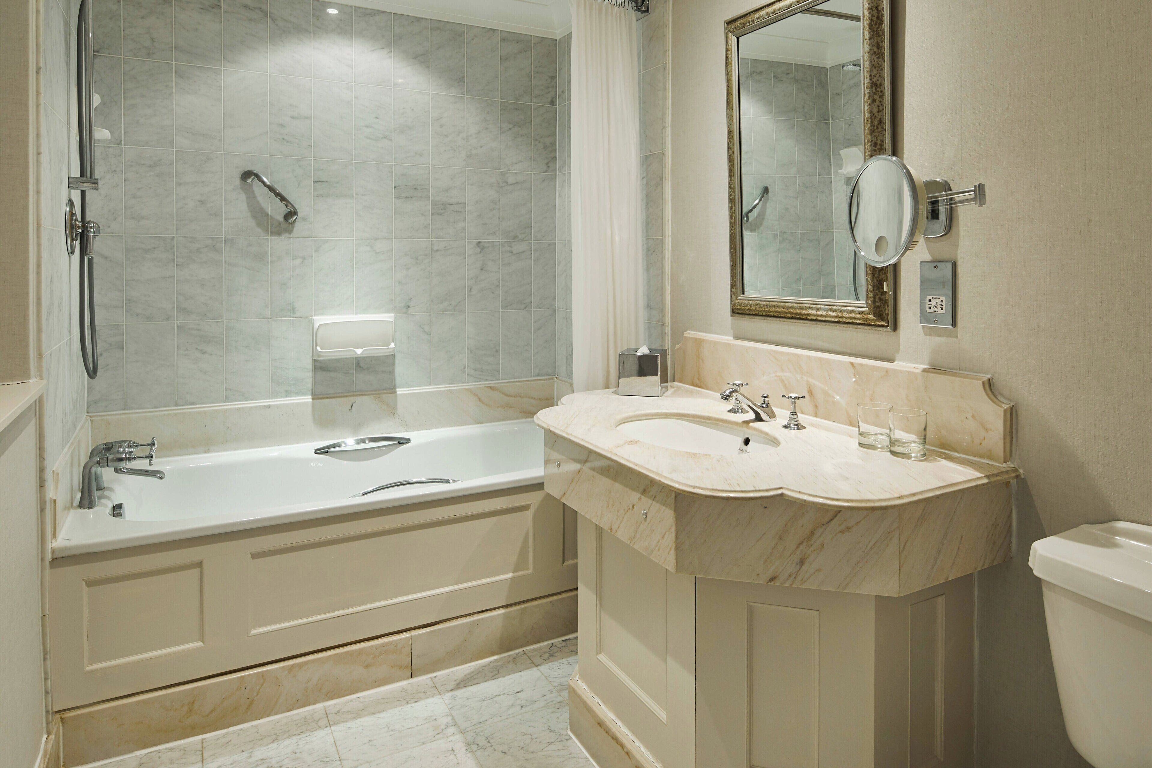 A bathroom with a bathtub, a sink, a toilet, and a mirror.