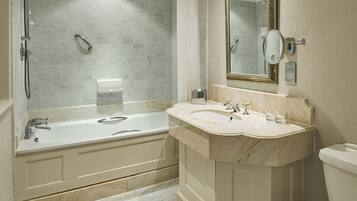 A bathroom with a bathtub, a sink, a toilet, and a mirror.