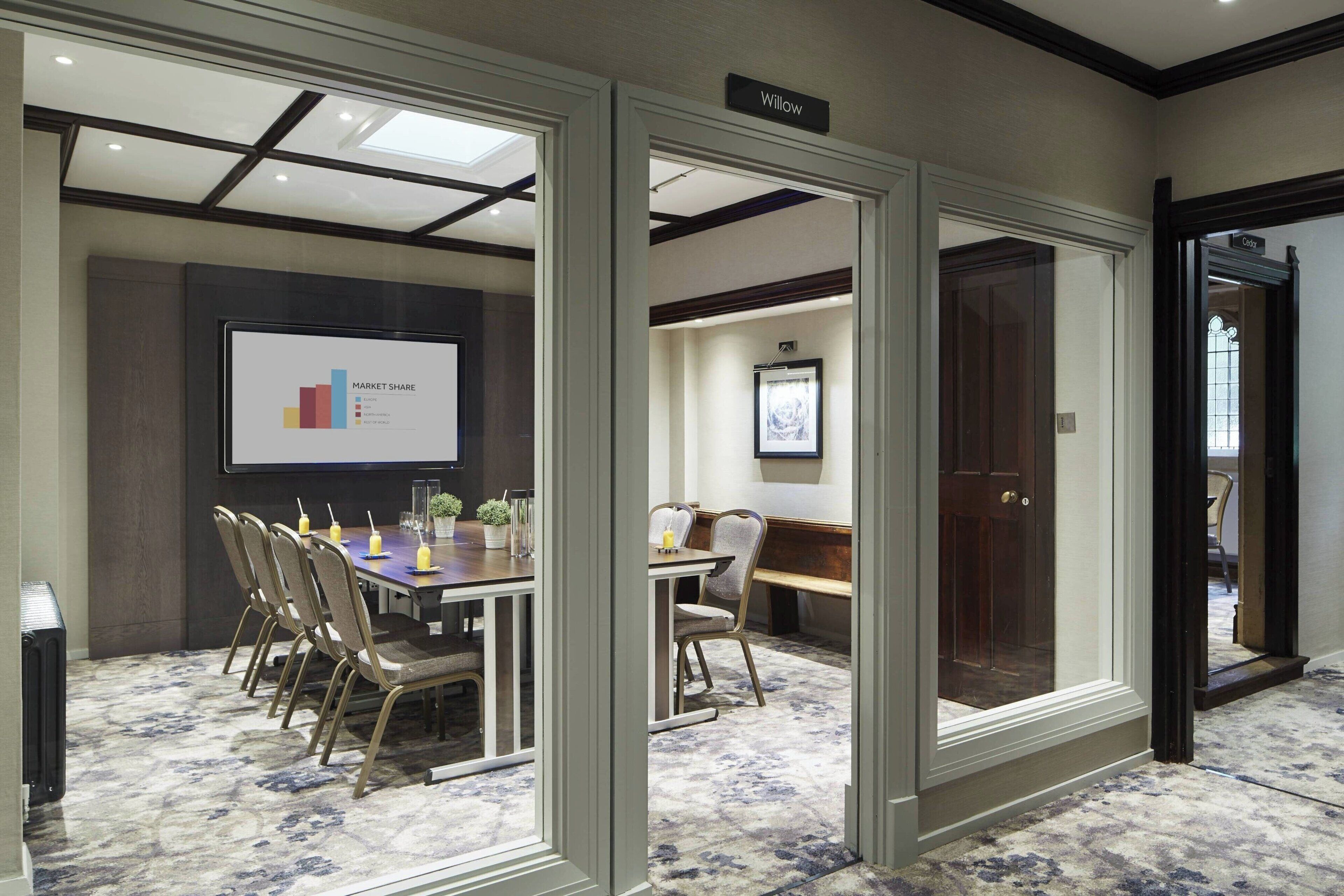 A conference room with a large screen displaying a market share graph, a long table with chairs, and a carpeted floor.