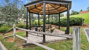 A gazebo with a wooden roof and metal frame, surrounded by a gravel path and green grass. - Red Roof Inn Johnson City (Johnson City)