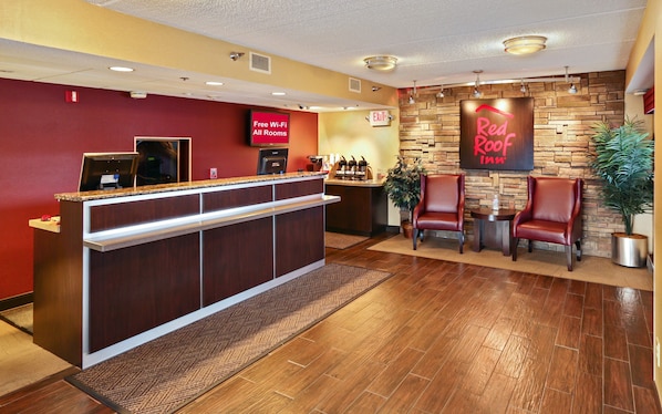 A hotel reception area with a reception desk, a sign indicating free Wi-Fi in all rooms, and a Red Roof Inn sign on the wall. - Red Roof Inn Johnson City (Johnson City)