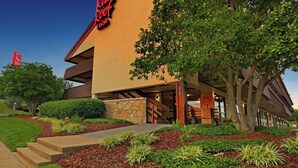 A building with a red sign reading 'Red Roof Inn' and a stone wall entrance. - Red Roof Inn Johnson City (Johnson City)
